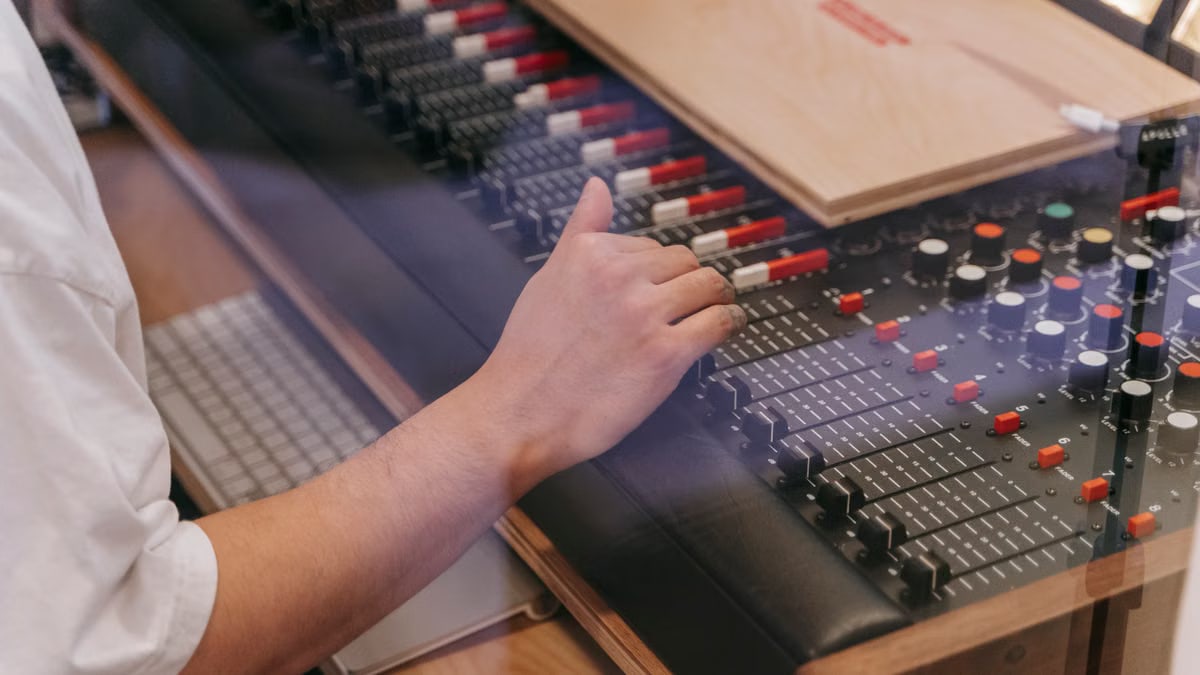 Close-up of an audio engineer's hand adjusting a mixing console in a recording studio.