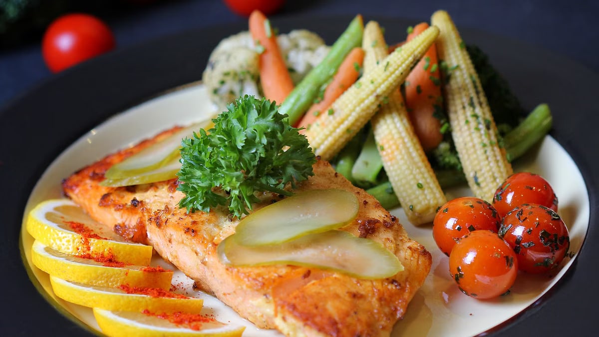 A beautifully plated salmon dish with fresh vegetables and lemon slices, perfect for a gourmet meal.